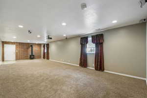 Interior space featuring a wood stove, brick wall, carpet floors, and a textured ceiling