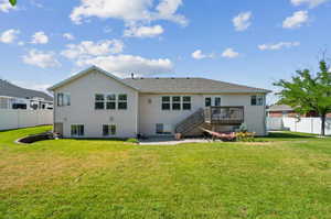 Back of house featuring a patio area, a lawn, and a wooden deck