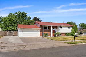 Bi-level home featuring a garage and a front lawn