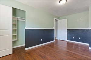 Unfurnished bedroom with dark hardwood / wood-style floors, a closet, and a textured ceiling