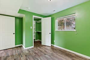 Unfurnished bedroom with a spacious closet, a textured ceiling, hardwood / wood-style flooring, and a closet