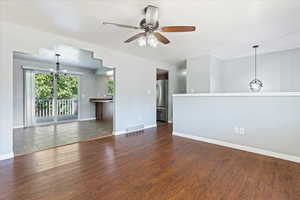 Unfurnished living room with dark wood-type flooring and ceiling fan with notable chandelier