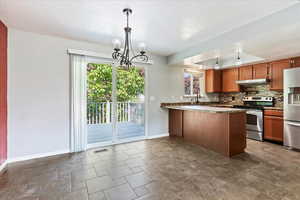 Kitchen with decorative light fixtures, a healthy amount of sunlight, tasteful backsplash, and stainless steel appliances