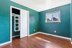 Unfurnished bedroom with a closet and dark wood-type flooring