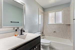 Full bathroom with tile patterned floors, toilet, vanity, and shower / bathtub combination