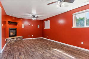 Unfurnished living room with ceiling fan, a fireplace, and dark hardwood / wood-style flooring