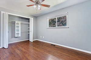 Unfurnished bedroom featuring dark wood-type flooring, a closet, and ceiling fan