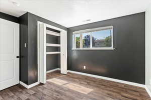 Unfurnished bedroom featuring dark wood-type flooring, a closet, and a textured ceiling