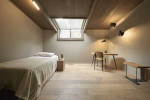 Bedroom with wood ceiling and light hardwood / wood-style floors