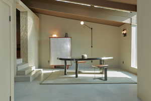 Unfurnished dining area featuring concrete flooring and vaulted ceiling with beams