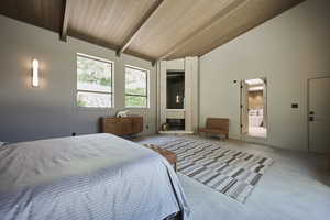 Carpeted bedroom featuring a fireplace, ensuite bath, beamed ceiling, brick wall, and wood ceiling