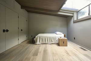 Unfurnished bedroom with a skylight, beamed ceiling, and light hardwood / wood-style floors