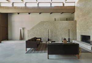 Living room featuring a stone fireplace, a towering ceiling, and concrete floors