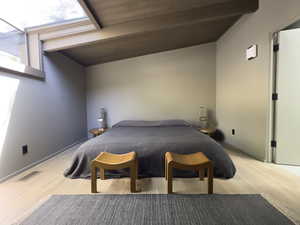 Bedroom featuring lofted ceiling with skylight and wood-type flooring