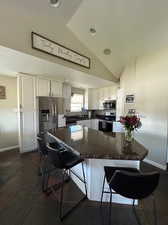 Fully updated kitchen featuring ample white cabinets, stainless steel appliances, granite countertops, lofted ceiling