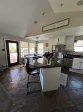 Updated Kitchen with white cabinets, a kitchen island / breakfast bar, stainless steel finishes and decorative light fixtures