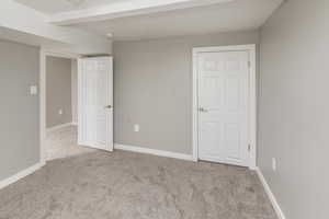 Unfurnished room featuring beamed ceiling and light colored carpet