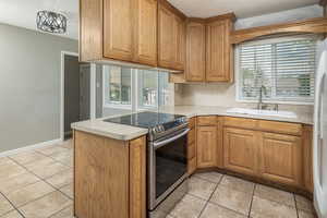 Kitchen featuring plenty of natural light, light tile patterned floors, sink, and stainless steel range with electric stovetop