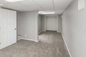 Basement with carpet and a paneled ceiling