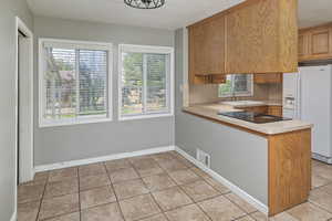 Kitchen featuring sink, white fridge with ice dispenser, a healthy amount of sunlight, and light tile patterned flooring