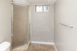 Bathroom featuring tile patterned floors, walk in shower, and toilet