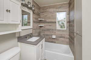 Full bathroom featuring vanity, tiled shower / bath combo, and toilet