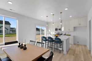 Dining space with a healthy amount of sunlight and light hardwood / wood-style flooring