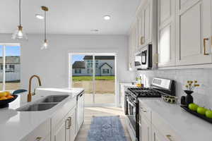 Kitchen with sink, appliances with stainless steel finishes, white cabinetry, and backsplash