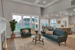 Living room with a notable chandelier, light wood-type flooring, coffered ceiling, a towering ceiling, and sink