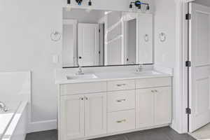 Bathroom featuring double sink vanity, a bathing tub, and tile patterned flooring