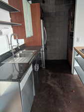 Kitchen featuring dark stone counters, stainless steel appliances, and sink