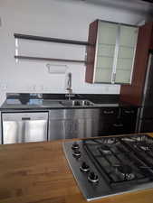 Kitchen with fridge, stainless steel dishwasher, hardwood / wood-style floors, gas cooktop, and sink