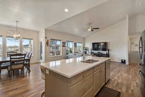 Kitchen with dark wood-type flooring, lofted ceiling, sink, and an island with sink