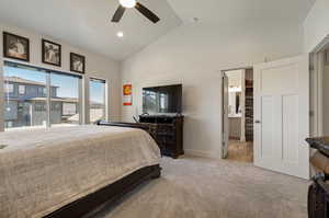 Carpeted bedroom featuring connected bathroom, ceiling fan, and high vaulted ceiling