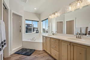 Bathroom featuring independent shower and bath, a textured ceiling, wood-type flooring, and dual bowl vanity