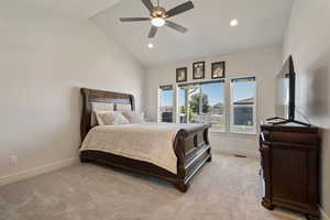 Carpeted bedroom featuring ceiling fan and high vaulted ceiling