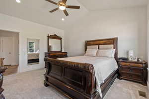 Bedroom featuring ceiling fan, vaulted ceiling, and light colored carpet