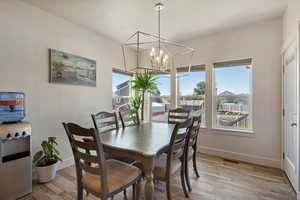 Dining area with hardwood / wood-style floors and an inviting chandelier