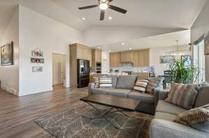 Living room featuring sink, high vaulted ceiling, ceiling fan with notable chandelier, and hardwood / wood-style floors