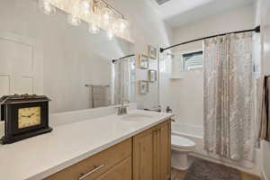 Full bathroom featuring wood-type flooring, shower / bath combo with shower curtain, toilet, and vanity