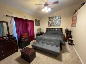 Carpeted bedroom featuring ceiling fan and vaulted ceiling