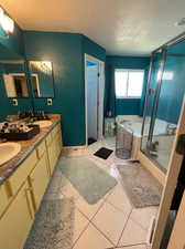 Bathroom with shower with separate bathtub, a textured ceiling, dual vanity, and tile patterned flooring