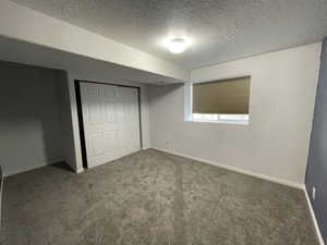 Unfurnished bedroom with a textured ceiling, carpet flooring, and a closet