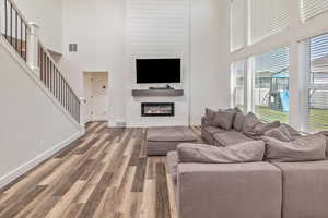 Living room with a fireplace, hardwood / wood-style floors, and a high ceiling