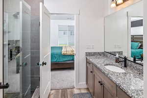 Bathroom with vanity, a tile shower, and hardwood / wood-style flooring