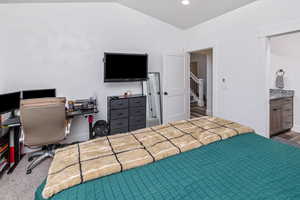 Bedroom with ensuite bathroom, wood-type flooring, and lofted ceiling