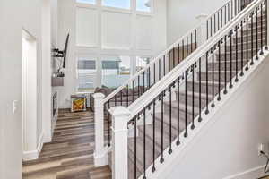 Staircase with hardwood / wood-style flooring and a high ceiling