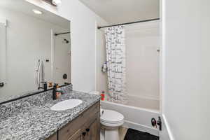 Full bathroom featuring hardwood / wood-style flooring, vanity, shower / tub combo, and toilet