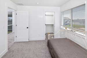 Unfurnished bedroom featuring a walk in closet, a closet, and light colored carpet