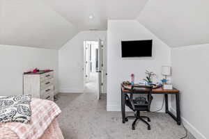 Bedroom with light carpet, a textured ceiling, and vaulted ceiling